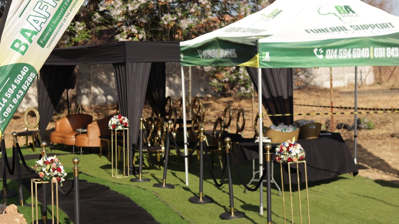 BaAfrica staff setting up a branded gazebo and feather flags before a service