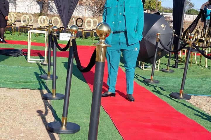 A BaAfrica graveside setup with red carpet runner and draped gazebo