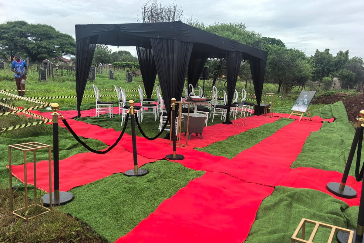 A fully appointed BaAfrica graveside setup with red carpet, gold stanchions and floral arrangements