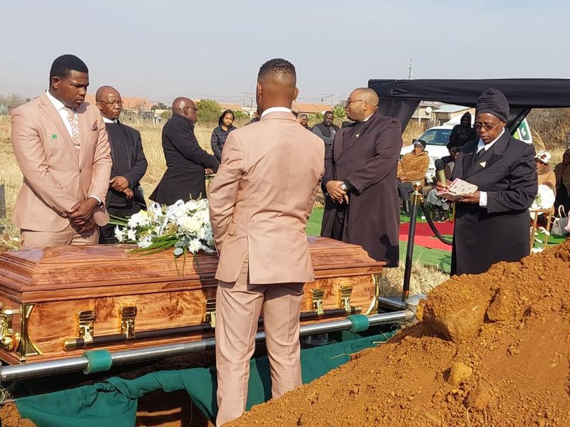 A BaAfrica committal at the graveside, with the casket on the lowering frame and staff in attendance