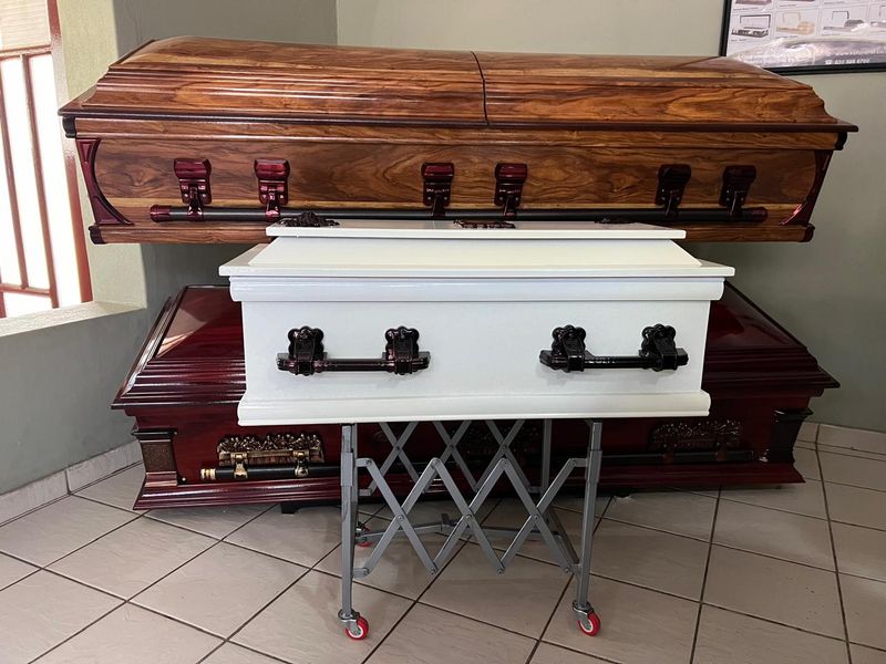 A polished mahogany casket and a white casket on display in the BaAfrica showroom