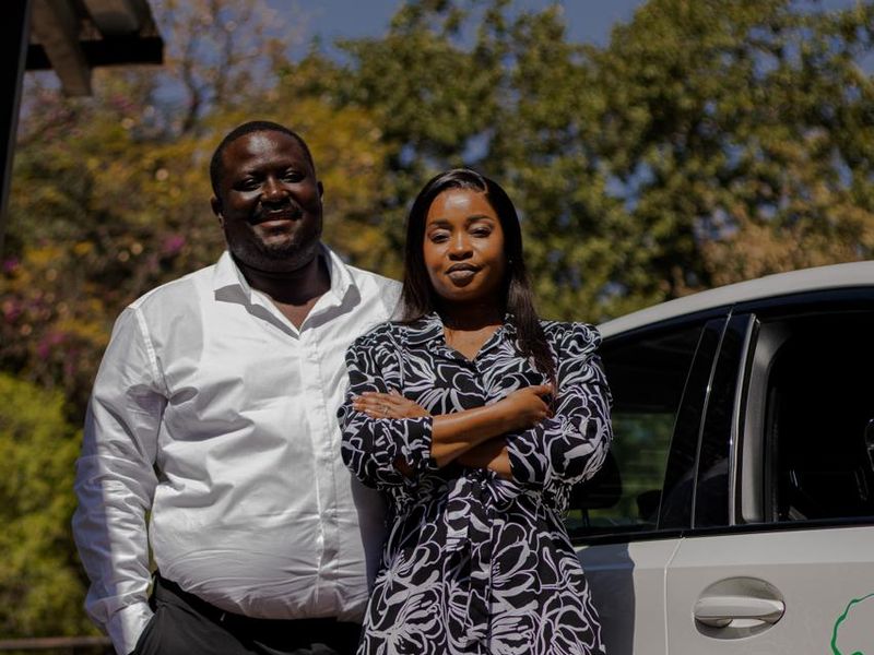Two BaAfrica consultants standing beside a branded company car