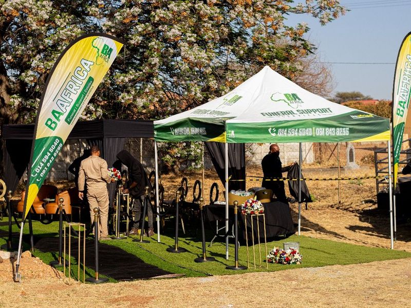BaAfrica staff setting up a branded gazebo and feather flags before a service