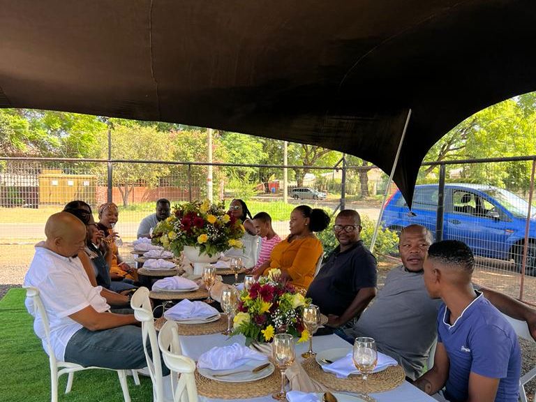 A BaAfrica grocery handover to a family, with flowers presented